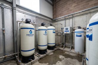 Adoucisseur d'eau industriel installé dans une salle technique d'entreprise avec tuyauterie en acier inoxydable