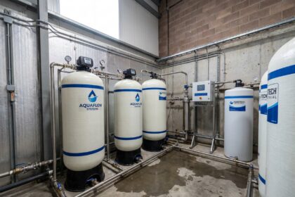 Adoucisseur d'eau industriel installé dans une salle technique d'entreprise avec tuyauterie en acier inoxydable